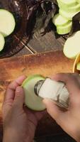 Vertical . Making veggies for summer dinner in nature. Hands adding salt to raw zucchini slices. video