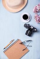 Workspace seen from above a table with an analog camera, a coffee and a notebook. photo