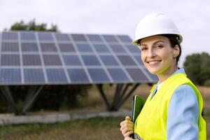 Portrait of a happy female Solar energy engineer or technician in a rural field with solar panel structure at background. Copy space photo