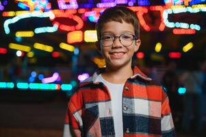 A cute Caucasian boy, a child, came to the amusement park to have fun, play and ride a merry-go-round. A child standing in front of a merry go round photo
