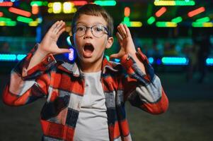 A cute boy happily spends time in an amusement park. Concept of happy childhood and holidays. photo