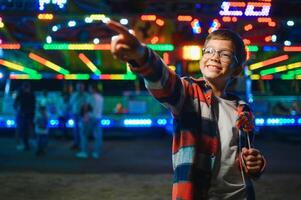 A cute boy happily spends time in an amusement park. Concept of happy childhood and holidays. photo