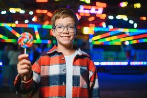 A cute Caucasian boy, a child, came to the amusement park to have fun, play and ride a merry-go-round. A child standing in front of a merry go round photo