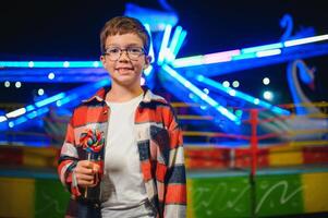 A cute Caucasian boy, a child, came to the amusement park to have fun, play and ride a merry-go-round. A child standing in front of a merry go round photo
