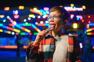 A cute Caucasian boy, a child, came to the amusement park to have fun, play and ride a merry-go-round. A child standing in front of a merry go round photo