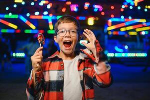 A cute Caucasian boy, a child, came to the amusement park to have fun, play and ride a merry-go-round. A child standing in front of a merry go round photo