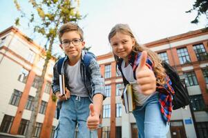 Happy school kids friends boy and girl with backpacks walking and laughing having fun together near school building outside outdoor after lessons photo