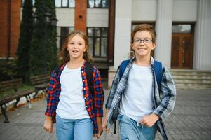 Two, little child with backpack near the school, after finished lesson and speak with each other photo