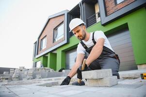 worker lay paving tiles, construction of brick pavement, men's hands in gloves. photo