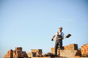 construction mason worker bricklayer installing red brick with trowel putty knife outdoors photo