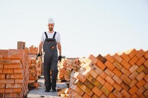 Installing brick wall. Construction worker in uniform and safety equipment have job on building photo