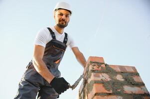 Installing brick wall. Construction worker in uniform and safety equipment have job on building photo