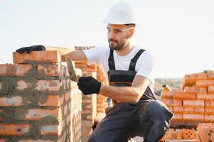 Construction worker man in work clothes and a construction helmet. Portrait of positive male builder in hardhat working at construction site photo