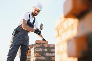 Construction worker man in work clothes and a construction helmet. Portrait of positive male builder in hardhat working at construction site photo