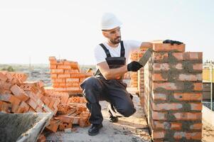 Construction worker man in work clothes and a construction helmet. Portrait of positive male builder in hardhat working at construction site photo