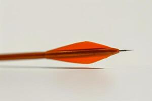 A vibrant orange arrowhead rests on a smooth surface during an archery session photo