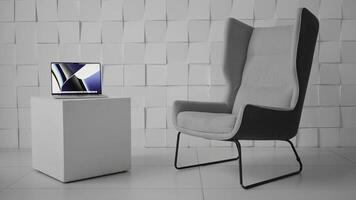 Laptop on a cubic shaped coffee table in a modern office. Action. Minimalistic design of the room with a comfortable chair and a computer on a small table. photo