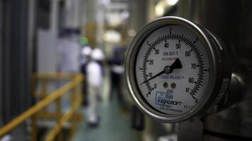 Close up of hydraulic pressure gauge at the factory. Scene. Blurred background with workers in a narrow corridor of a workshop. photo