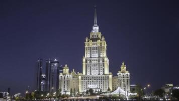 Late night cityscape with illuminated skyscraper in Moscow designed in the Stalinist style. Action. Beautiful building on a dark blue evening sky background, concept of architecture. photo