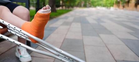 Prominently featured orange-casted leg in the foreground, with the tranquil scenery of a summer park providing the out-of-focus background, copy space photo
