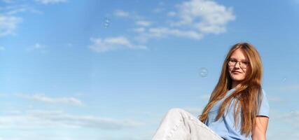 Silhouetted by the vibrant azure backdrop, a female subject's expression is heightened by the presence of her glasses, resulting in a contemplative, enigmatic portrait photo