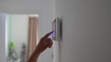 Closeup hand using smart home panel, touching screen with connected appliances device on wall. video