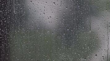 Rain droplets slide down windowpane, sunlight glimmers faintly outside. Overcast weather, depression video