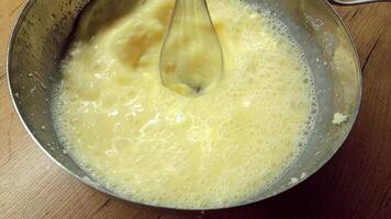 Chef person is mixing ingredients eggs, sugar, butter for bakery with electric mixer in the bowl close up. Preparing delicious pastry or dough to make cake. video