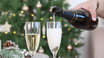Close-up of a glass into which sparkling wine or champagne is poured from a bottle. New Year and Christmas. Celebratory drink video