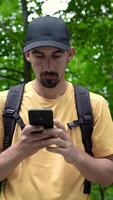 Man with backpack in forest uses phone looking for connection signal video