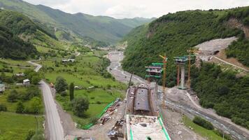 Kazbegi, Georgia - 7th july, 2024- aerial view cranes and bridge foundation pillars on construction site of new highway road project built by chinese builders.Avalanche bypass tunnel.Tbillisi - Lars video