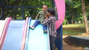 A father and child playing together in a city park playground, enjoying swings and slides. Perfect for projects focused on family bonding, outdoor activities, and childhood moments. video