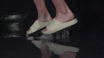 A joyful person splashes in water puddle with sandals, creating energy video
