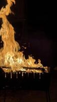 Flames rising high from a grill at night, creating a warm and dramatic atmosphere. video