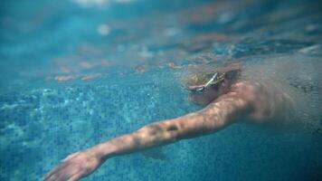 Underwater view of professional swimmer training in swimming pool, 4k 120 fps super slow motion raw . Triathlete swim in black wetsuit video