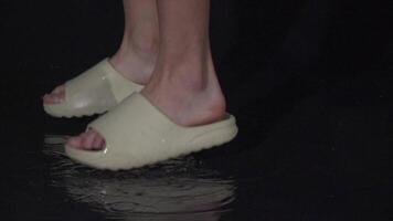 A joyful person splashes in water puddle with sandals, creating energy video