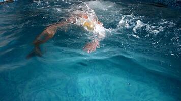 Underwater view of professional swimmer training in swimming pool, 4k 120 fps super slow motion raw . Triathlete swim in black wetsuit video