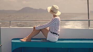 A woman travels on a large ferry, sits at the stern, and looks into the distance. Summer vacation video