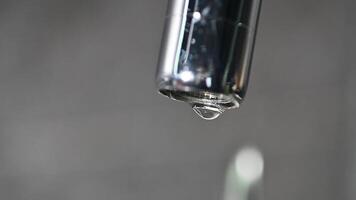 Drop of water drips from the tap. Beautiful fresh and clean water flowing Close-up front view broken chrome faucet in kitchen. Everyday problems, wasting water and energy video