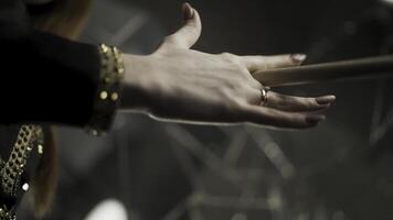 Young attractive woman hand holding drumstick and rotating it during musical rehearsal. Action. Close up for woman hand with manicure and gold rings holding and spinning a drumstick. photo