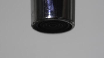 Extreme close up of the water flowing from the faucet and then stopping to flow. Media. Chrome water tap spout with flowing fresh water. photo