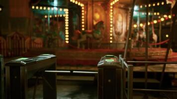 Empty amusement park at night with lit carousel and closed turnstiles video