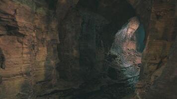 Exploring the dark cave with sunlight streaming through cracks at noon video