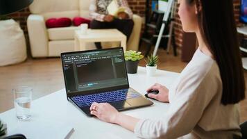 Asian female programmer works on coding software in a home office setup, typing code on a laptop. IT expert uses digital tools for multitasking, software development and app development. Camera A. video