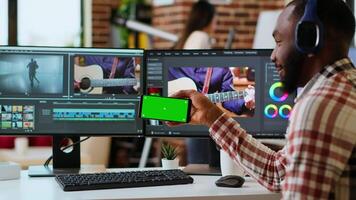 African american man edits a music at his home office next to copy space screen, using editing software and dual monitors. Solving production and freelancing tasks. Camera B. video