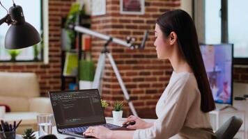 Asian freelancer woman works on programming code in a modern office at home, using her laptop for computer science. IT specialist supports coding, web development and digital innovation. Camera B. video
