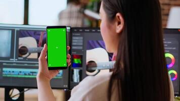 Asian woman working from home as a freelance editor, using isolated mockup display and mixing software. Creative workspace equipped with dual monitors and tech tools. Camera B. video