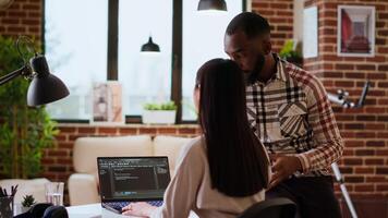 Interracial creative team programing code on a laptop and debugging, using digital tools at home. Professional coders team working on software development and internet security. Camera B. video