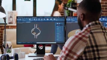 African american designer uses 3D modeling tools and CAD software for industrial projects. Working on creating prototypes and gears models for the manufacturing industry. Camera B. video