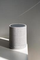 Modern gray speaker on table with soft shadows and light. photo